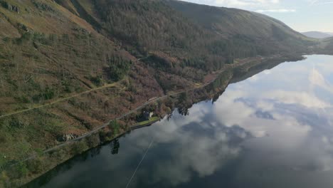 Cloud-reflections-and-lakeside-road-with-castle-like-structure-on-reservoir-shore