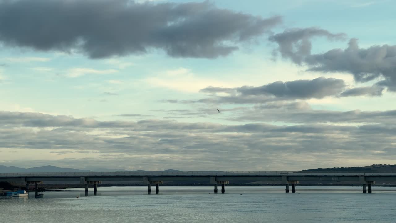 Wide shot of a bridge spanning calm ocean waters