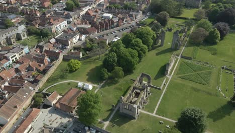 aerial view of the glastonbury abbey ruins an 8th century monastery and gardens. drone rotating to the left, ruins on the right and glastonbury town on the left. 4k, 60fps.