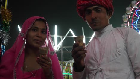 indian couple eating ice cream in traditional dresses at the pushkar mela, a carnival of rajasthan, india