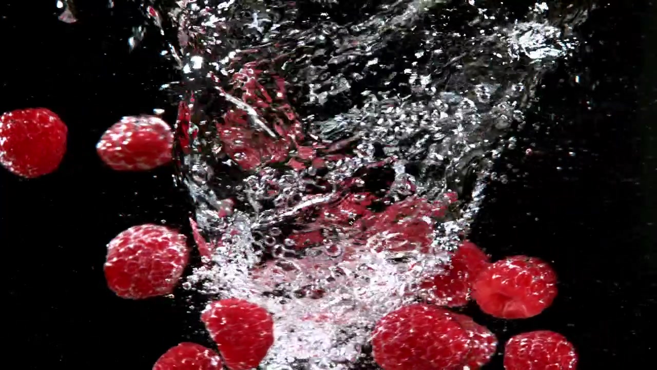 Fresh Raspberries Falling into Clear Water in Slow Motion