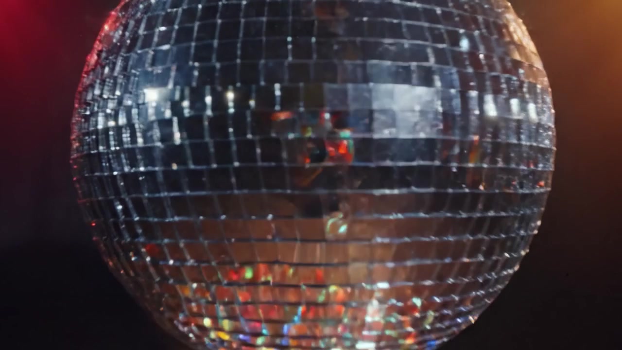 Una coinvolgente palla da discoteca che mostra riflessi colorati sotto vivaci luci da palcoscenico crea un'atmosfera festosa per momenti di ballo e celebrazione.
