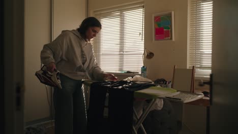cinematic shot of a woman ironing in a softly lit bedroom. natural morning light through blinds adds warmth and realism to this domestic irish interior.