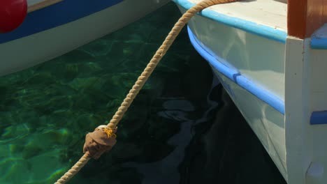 A-small-fishing-boat-anchored-at-the-port-of-Egliali-in-Greece,-the-reflections-on-the-water-are-magnificent,-Amorgos-island