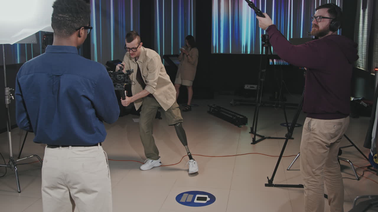 Smiling Cameraman With Prosthetic Leg Shooting Video In Studio