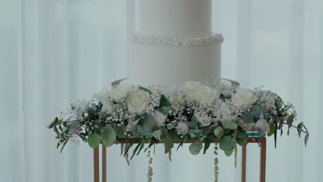 elegant white wedding cake atop floral arrangement