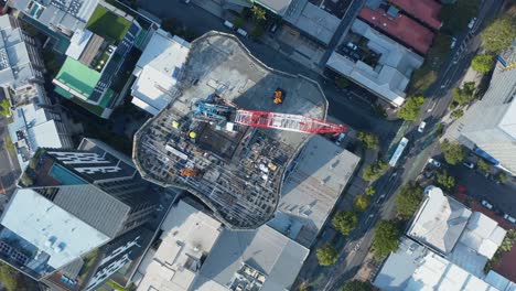 drone arriba abajo disparado volando sobre el extremo oeste mirando hacia abajo en el desarrollo de un gran edificio de apartamentos con grúa en el techo