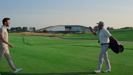 golf players shaking hands on grass field. two friends meeting play on weekend.