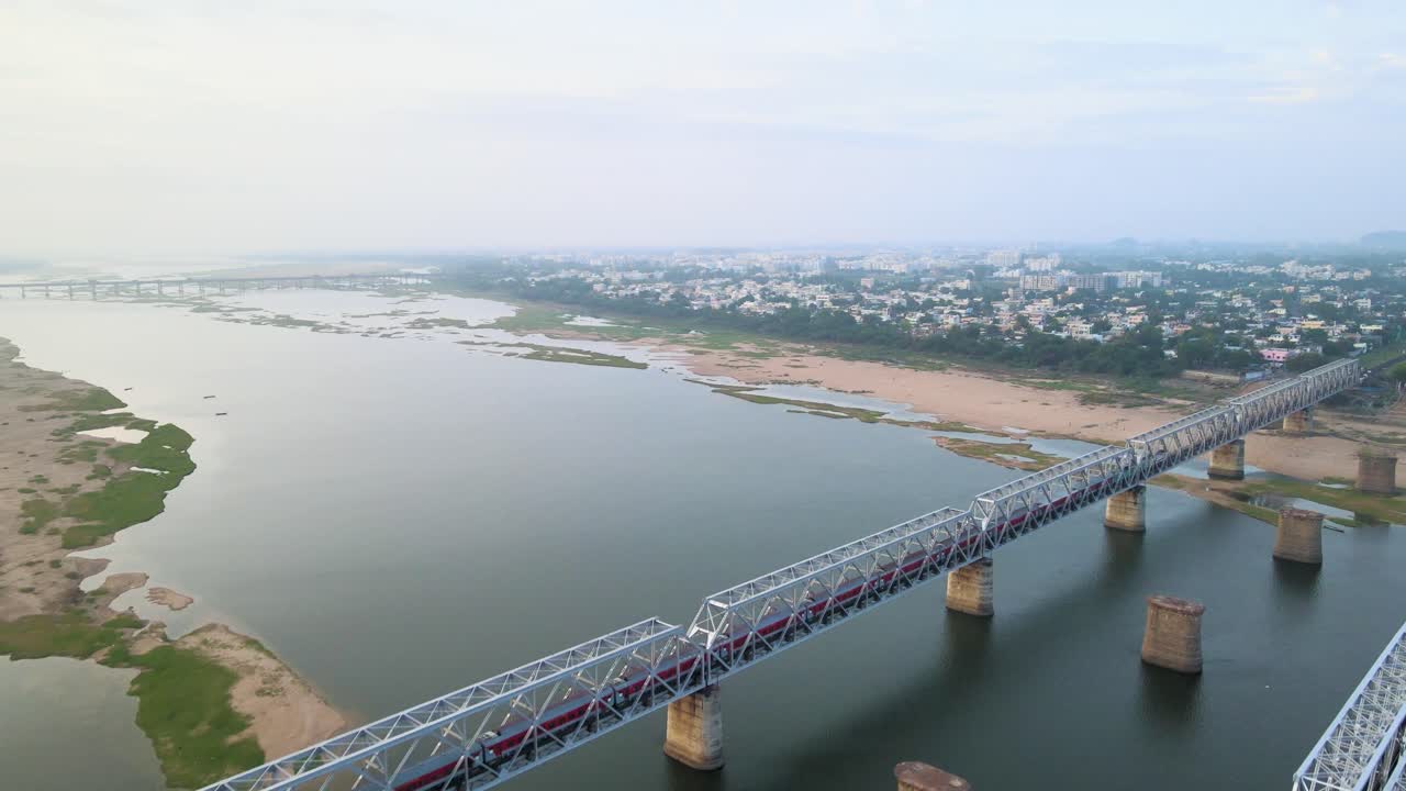 Aerial drone shot of an Indian train speeding through the bustling city, weaving between buildings and streets.