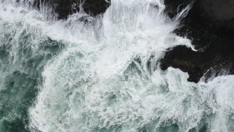 strong currents and foamy waves wash around the rocky coast line during a storm