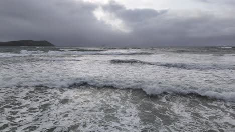 low drone over waves in sea stormy sky in background