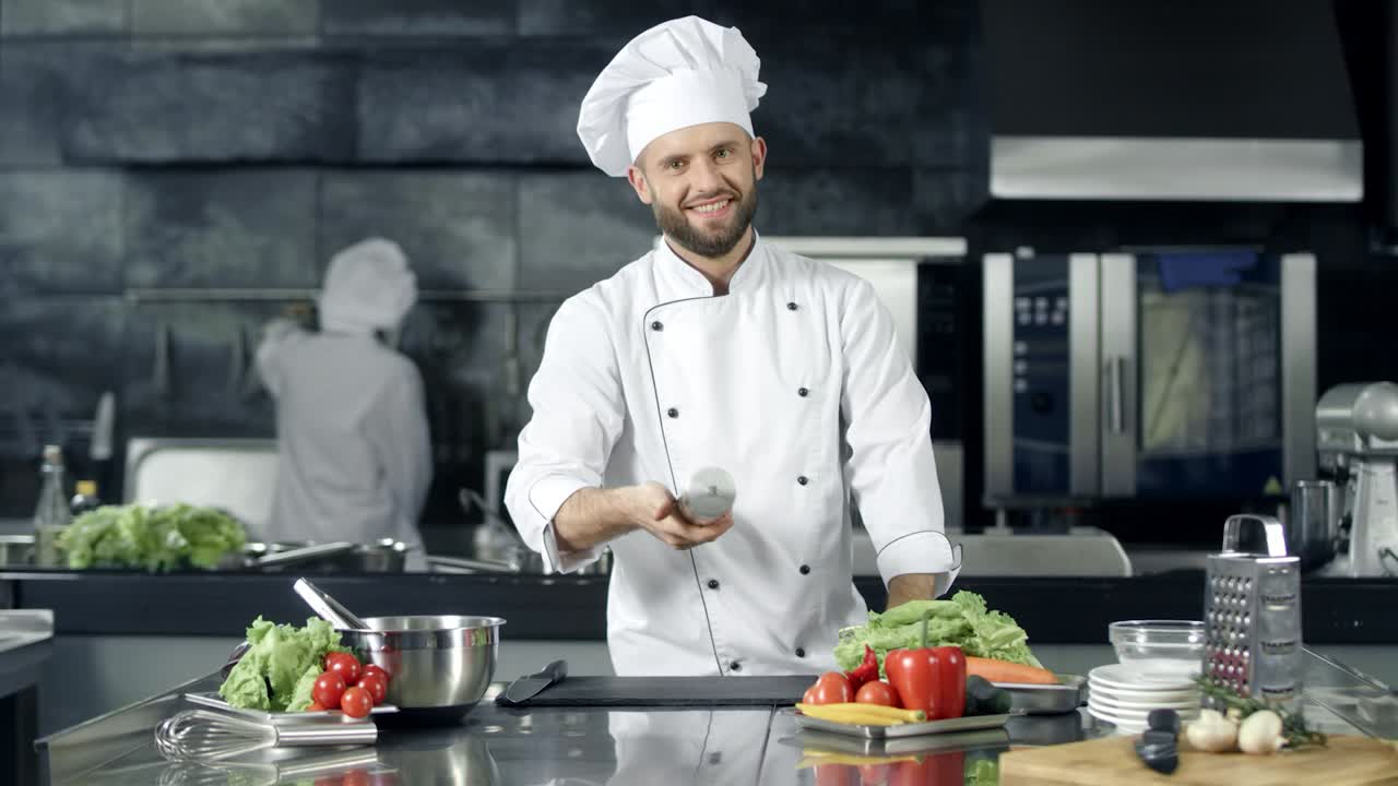 chef sonriente jugando con la caja de pimienta en el lugar de trabajo. trabajador feliz preparándose para cocinar