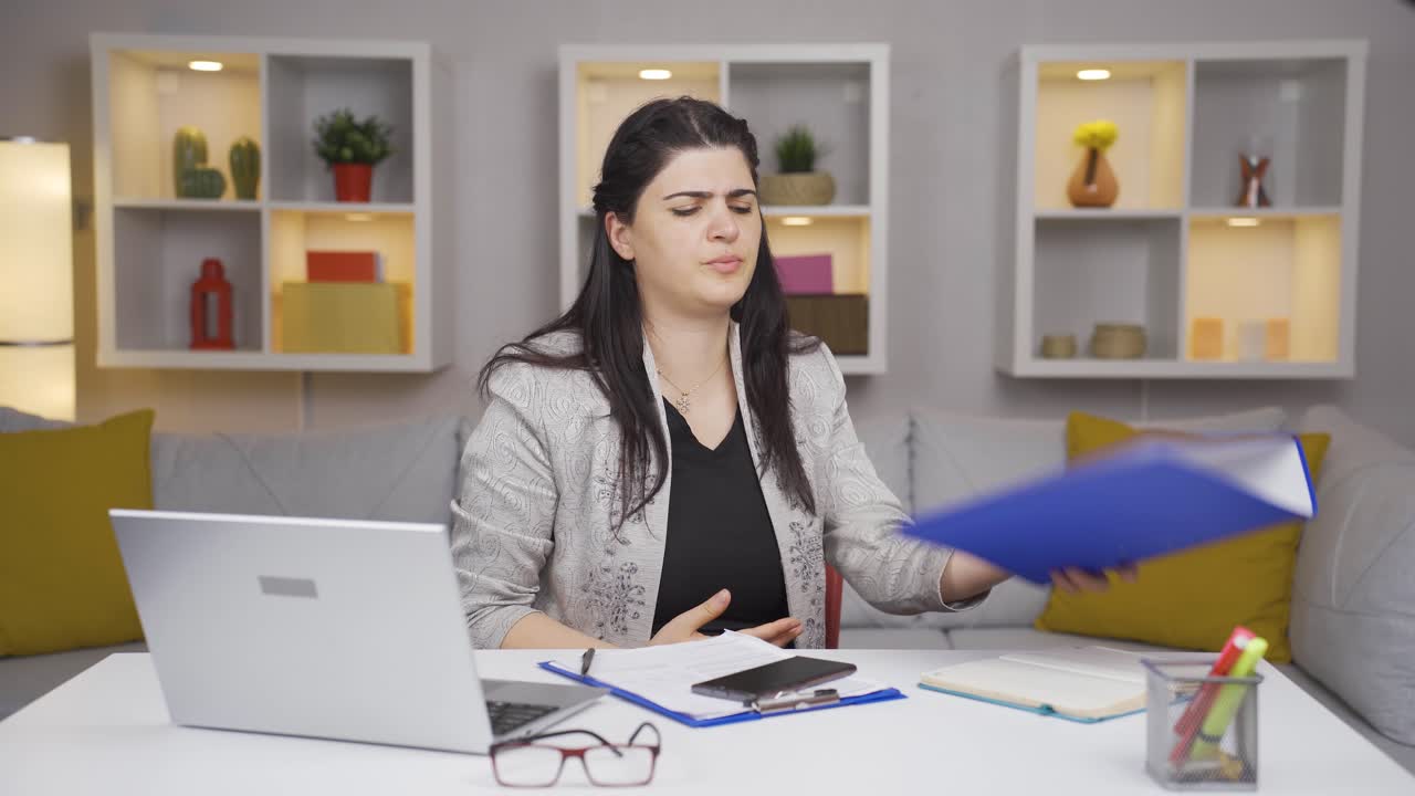 una trabajadora de oficina en casa mirando el archivo con enojo.