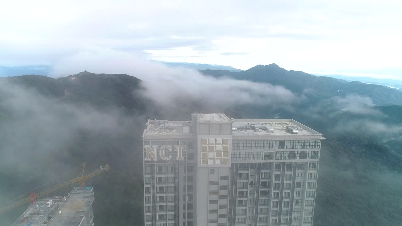 Aerial revealing shot of the Genting Highlands and the Grand ION Delemen hotel covered in fog.