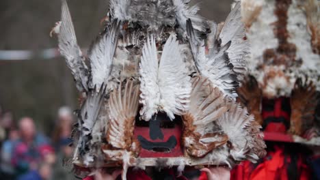 red mask with black mustache, vendetta alike but bulgarian kuker edition, decorated with chicken feathers