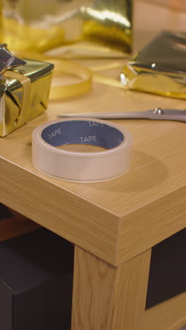 vertical video of gift or present being wrapped on table at home with scissors sticky tape and ribbon 2