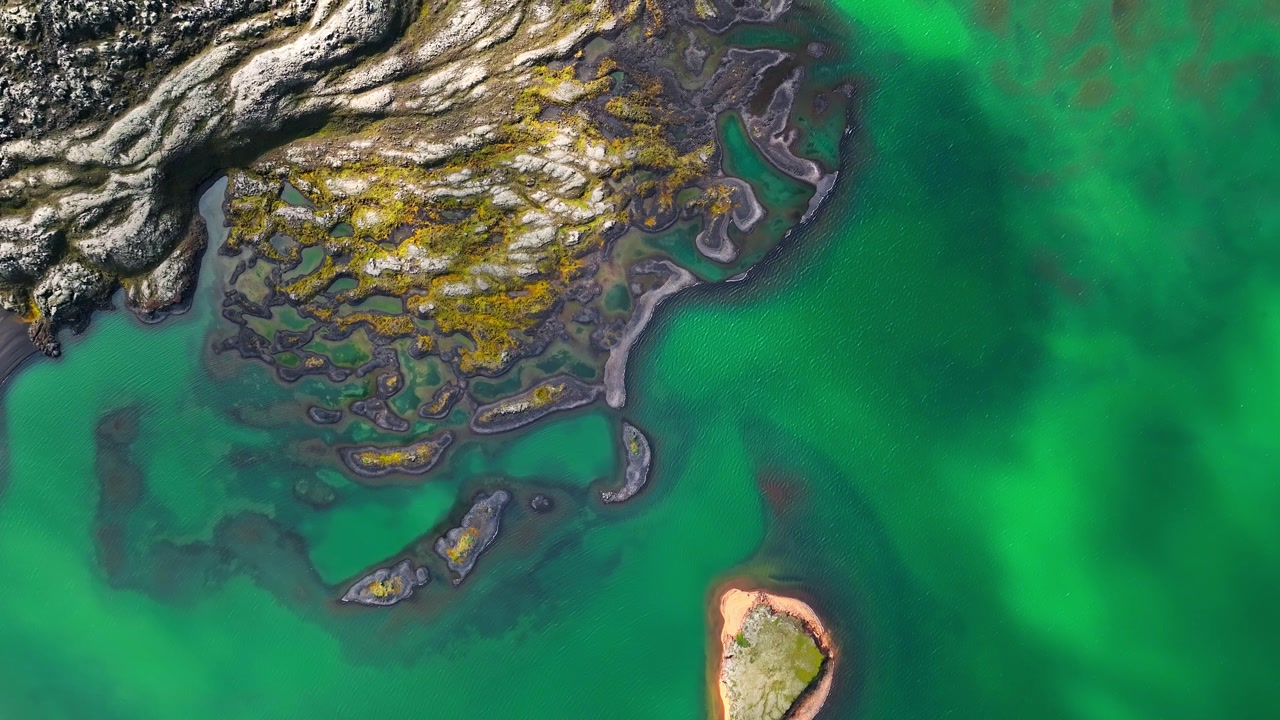 Aerial drone view of nature in Landmannalaugar in Iceland with colorful rhyolite lava field, and a cyan lake.