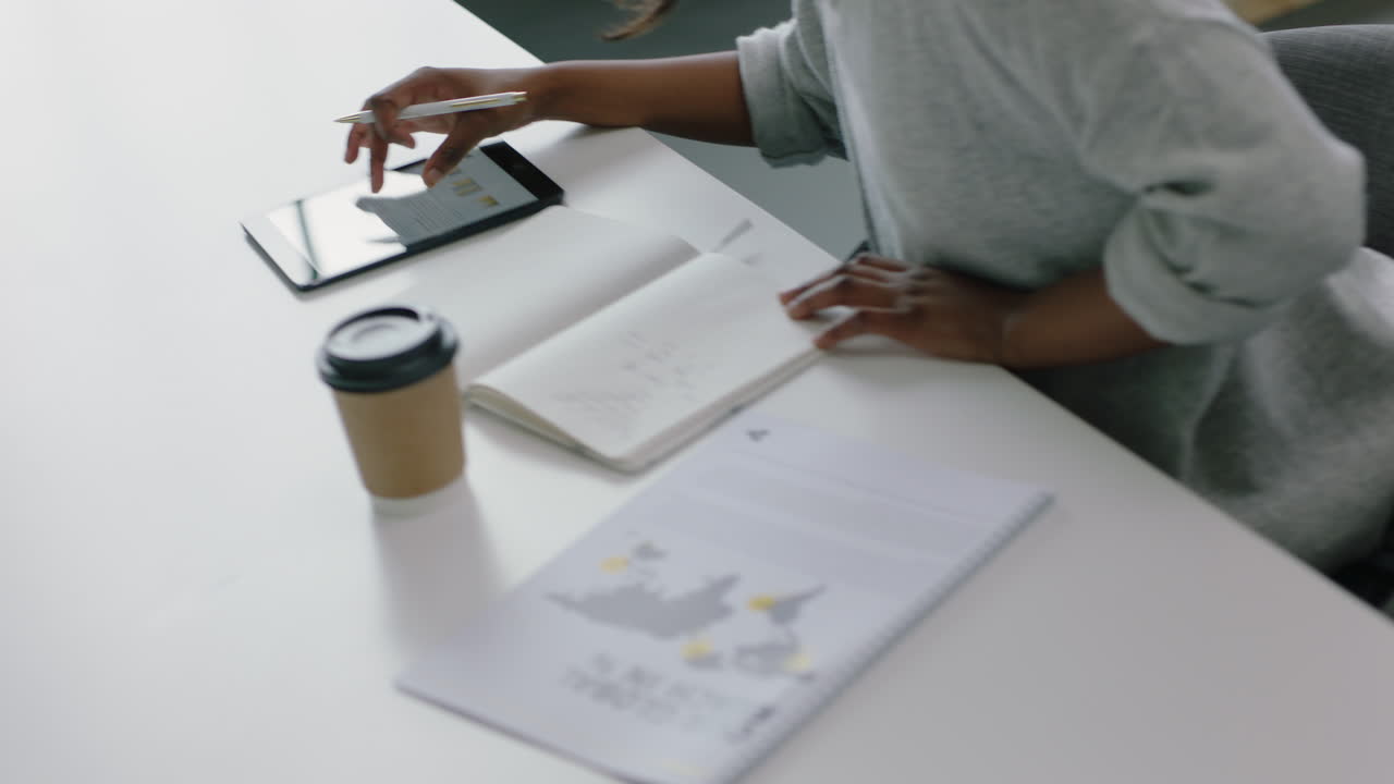 donna d'affari che utilizza un tablet computer, naviga dati di ricerca di mercato, fa brainstorming, sviluppa idee, scrive appunti, gode della tecnologia mobile in ufficio, sul posto di lavoro