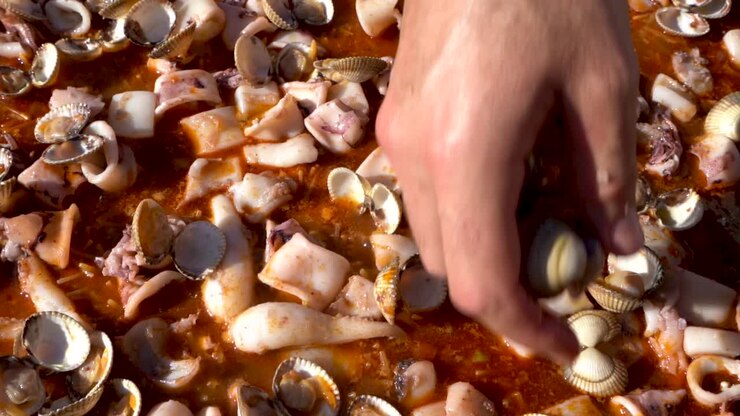 Putting seafood in paella, tasty, delicious dish from Spanish cuisine, slow motion