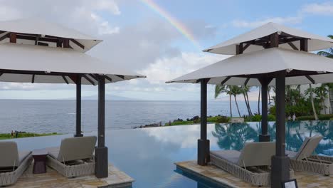 arco iris sobre el océano y la piscina infinita - panorámica hacia abajo