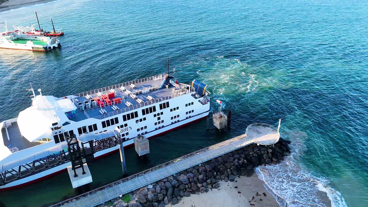 Aerial view of a ferry leaving the Queenscliff terminal. Clear skies, calm waters, and vibrant colors create a serene atmosphere