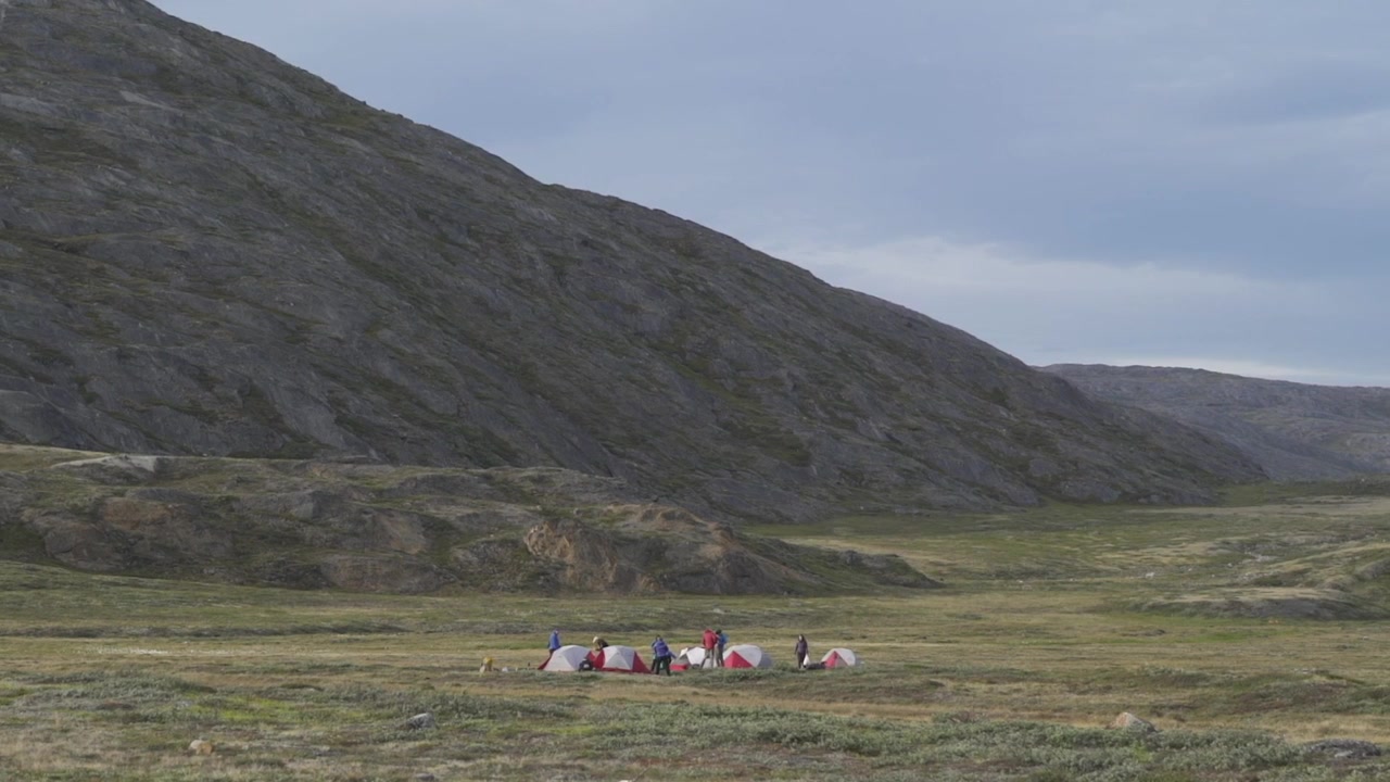 Group of hikers camping in remote mountain valley in wilderness of Greenland