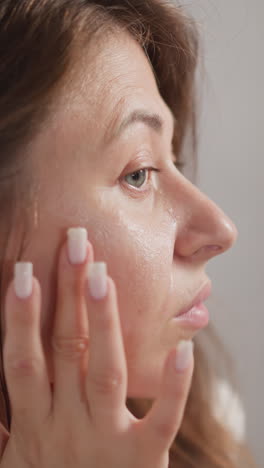 mujer aplica crema a la zona de la cara debajo de los ojos. mujer atractiva vigila cuidadosamente la piel de la cara tratando con cosméticos especiales en cámara lenta
