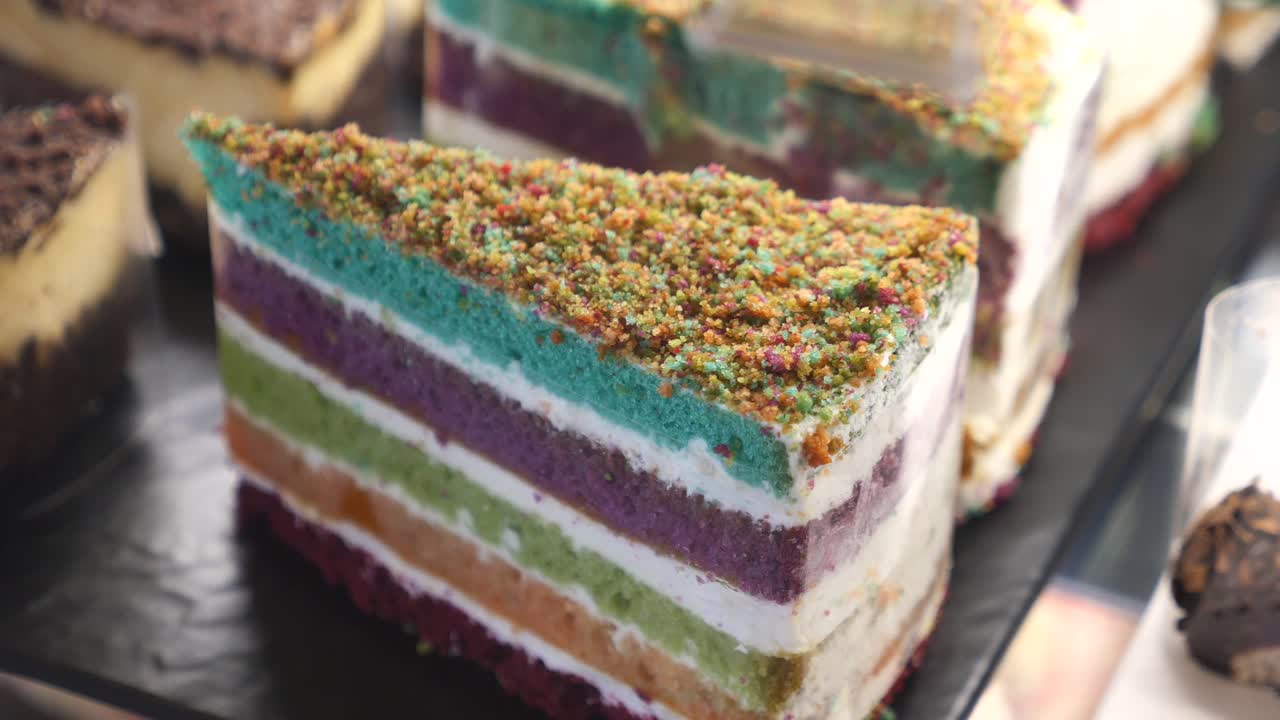 A vibrant slice of rainbow cake topped with colorful sprinkles