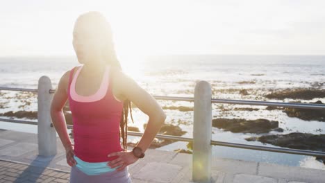 African-american-woman-in-sportswear-resting-on-promenade-by-the-sea