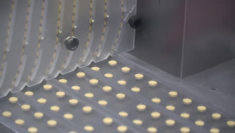 pharma lab circuit vertical machine and separator cascades yellow pills down into plastic reams, detail pan