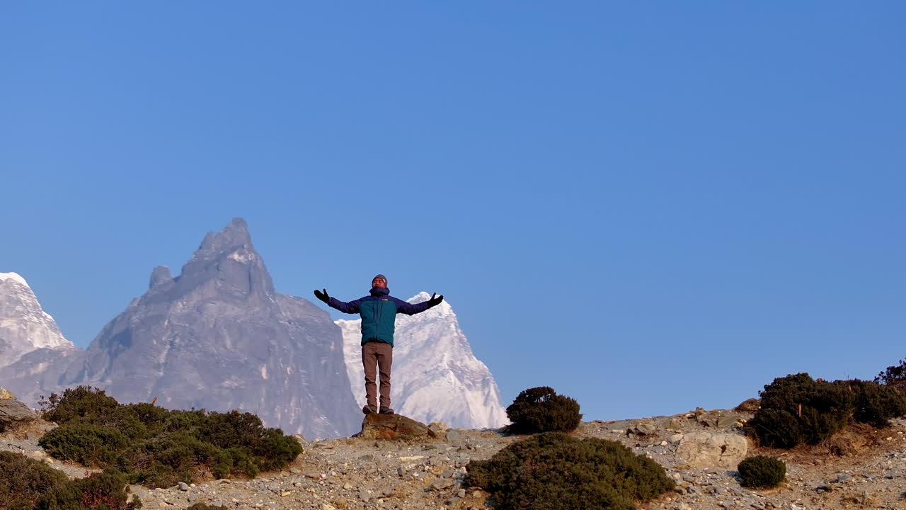 Drone shot of a male tourist inhaling fresh air and enjoying nature of Dingboche, Khumbu region, Nepal. Mt. Cholatse rises in backdrop under clear Himalayan skies on Everest Base Camp trek landscape