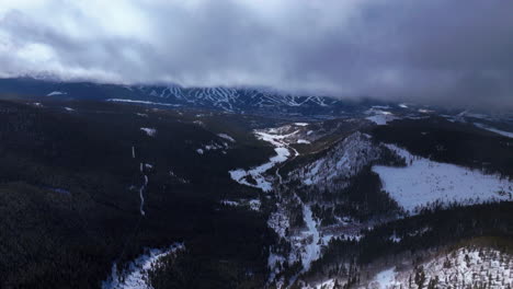 Cloud-fog-snow-layer-partially-sunny-Breckenridge-Ski-resort-town-Vail-Epic-Ikon-Pass-aerial-drone-Ten-Mile-Peaks-landscape-winter-morning-ski-trail-runs-Summit-County-Rocky-Mountains-forward-motion