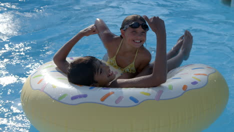 children having fun with inflatable in outdoor swimming pool