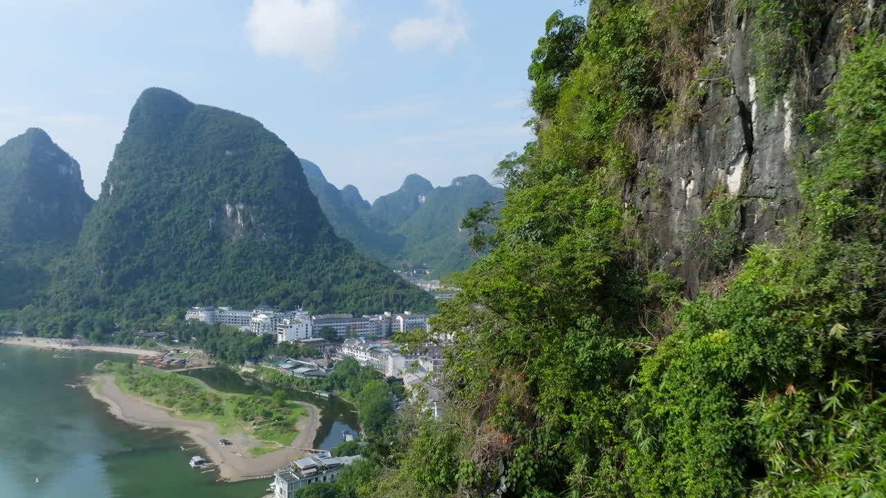 Drone seguindo uma parede de montanha, perto da vila de Yangshuo, em um dia ensolarado na China.