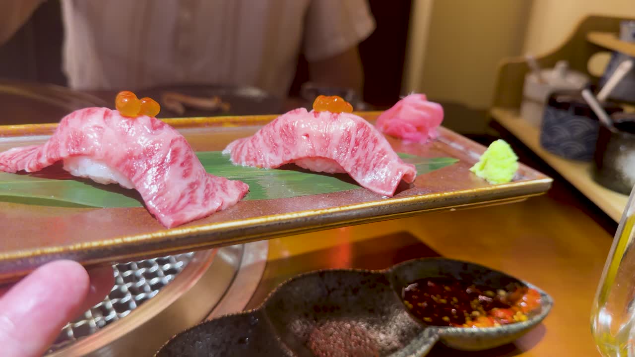 Cận cảnh sushi bò Wagyu vân cẩm thạch được gắp bằng đũa trong ánh sáng ấm áp