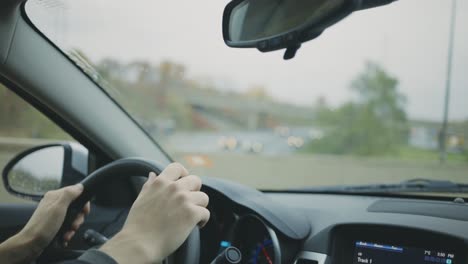 Hands-On-The-Steering-Wheel-While-Driving-On-The-Road-On-A-Rainy-Day---Travel-Concept---close-up