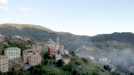 Vista-Aérea-De-Un-Pequeño-Pueblo-A-Través-De-Las-Montañas-En-Italia