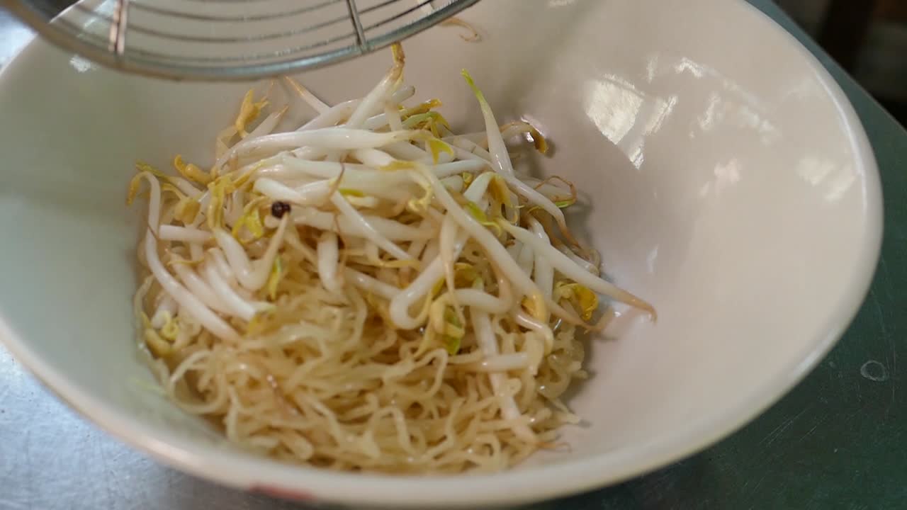 Close-Up Footage of Chef Adding Egg Noodles and Bean Sprouts into Bowl