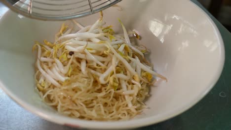 Close-Up-Footage-of-Chef-Adding-Egg-Noodles-and-Bean-Sprouts-into-Bowl