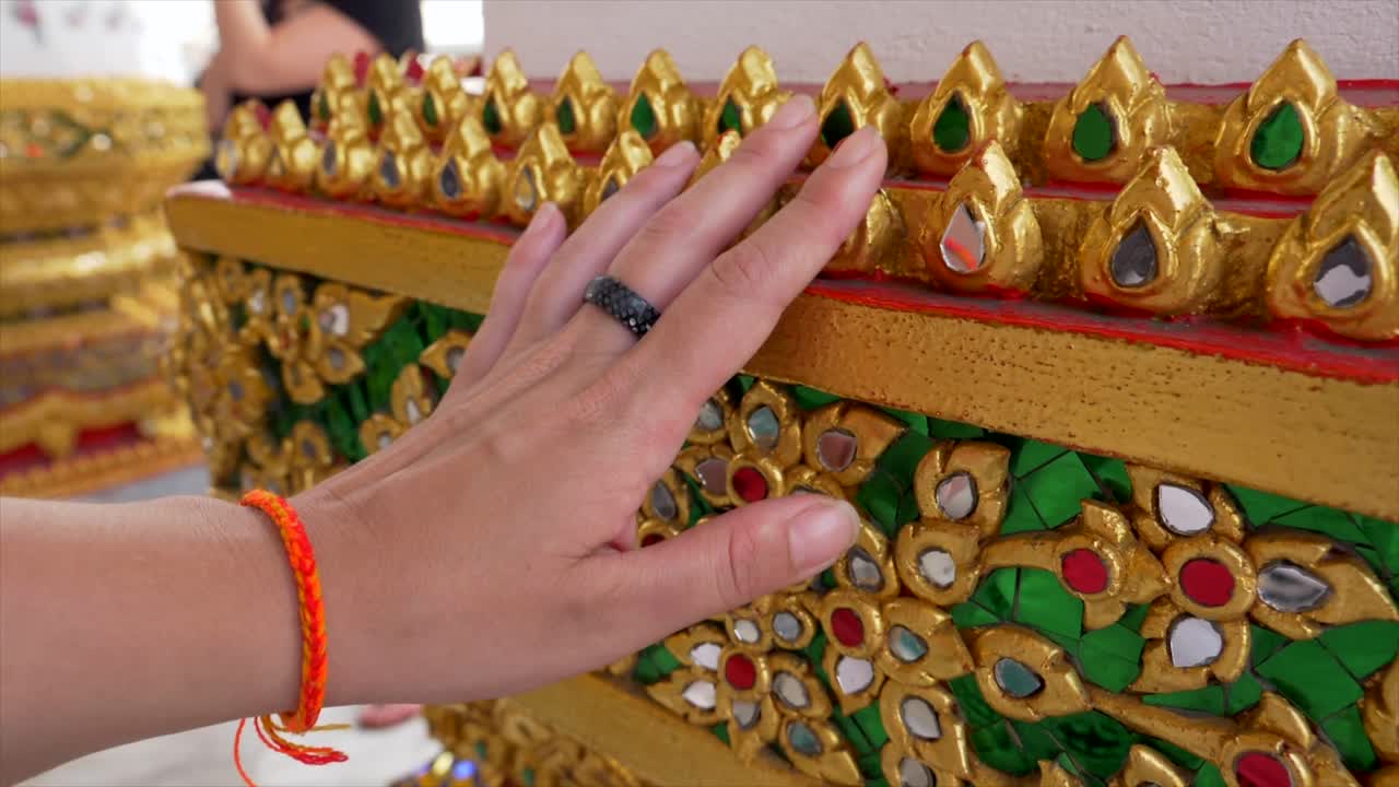 Slow motion shot of Hand touching the golden decorations of Wat Pho temple. Close-ups of intricate details. Perfect for travel, cultural, and religious themed projects.