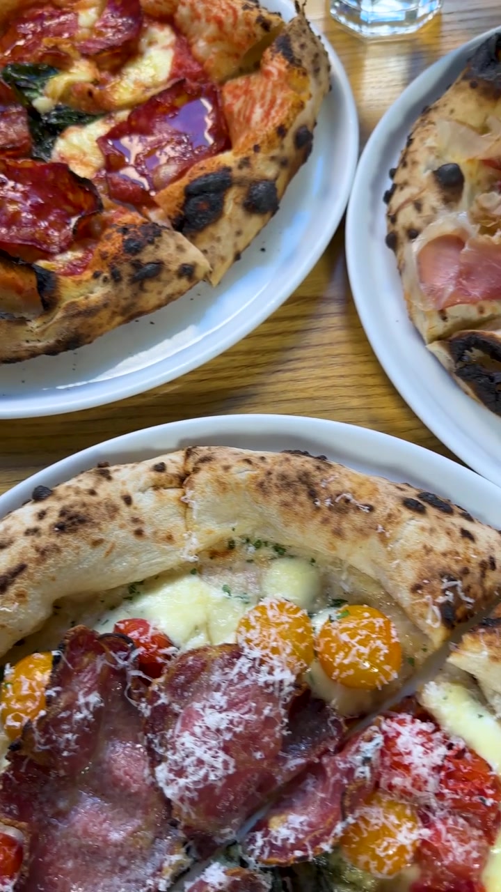 Paneo cenital de varias pizzas artesanales con ingredientes de primera calidad sobre una superficie de madera.