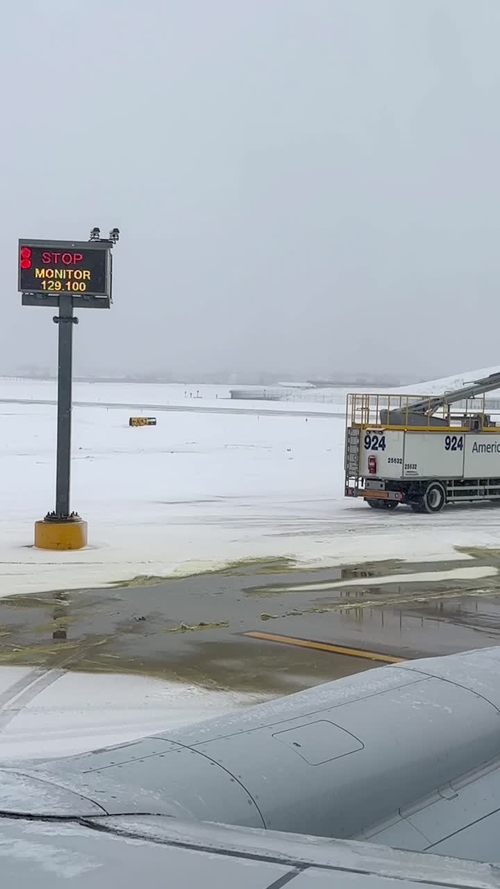 Un piazzale aeroportuale innevato con attrezzature per lo sghiacciamento e un segnale di stop visibile. Ideale per viaggi invernali o contenuti per l'industria aeronautica.