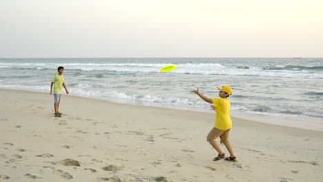 boys playing frisbee at the beach