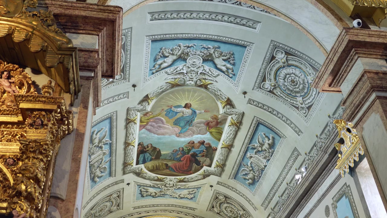Soffitto ornato di chiesa con dettagliati stucchi in stile barocco e un dipinto centrale che mostra Gesù che ascende al cielo.