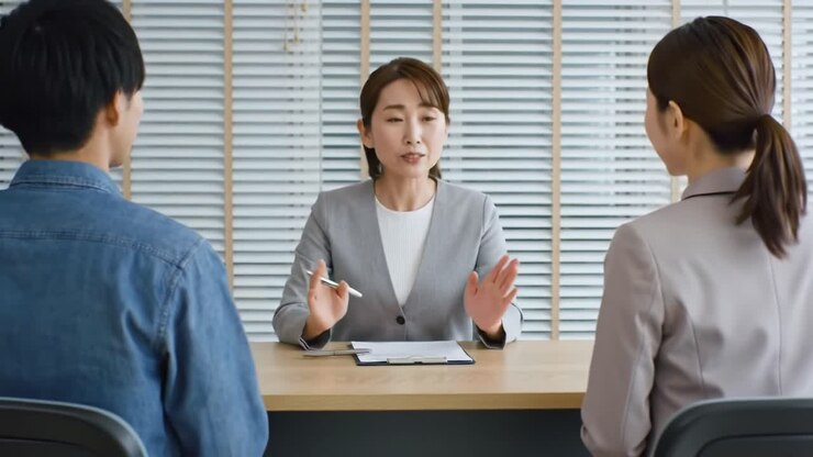Professional Interview Setting: A Confident Female Interviewer Engages with Candidates to Discuss Opportunities and Fit in a Brightly Lit Office Environment