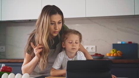 young woman with daughter chooses new recipes with tablet