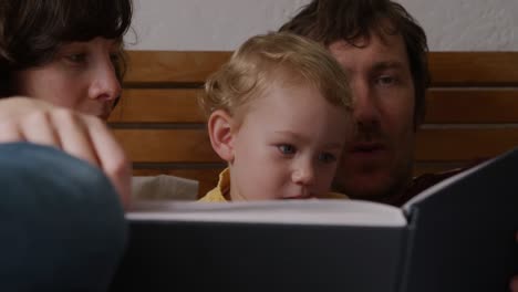 front view of couple reading book to baby at home