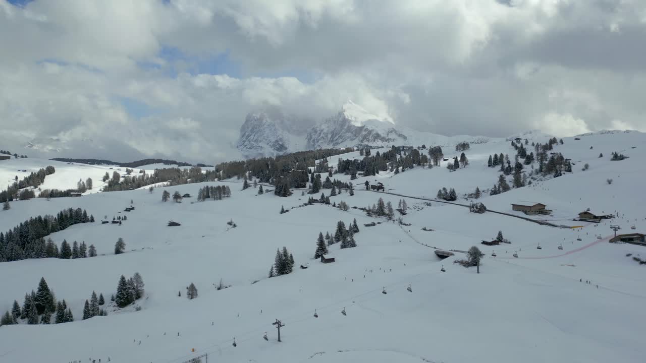 Beautiful scenic aerial view of snowy meadows and distant Alpe di Siusi Dolomites mountains in winter, Dolomites, Italy.