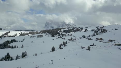 Beautiful scenic aerial view of snowy meadows and distant Alpe di Siusi Dolomites mountains in winter, Dolomites, Italy.