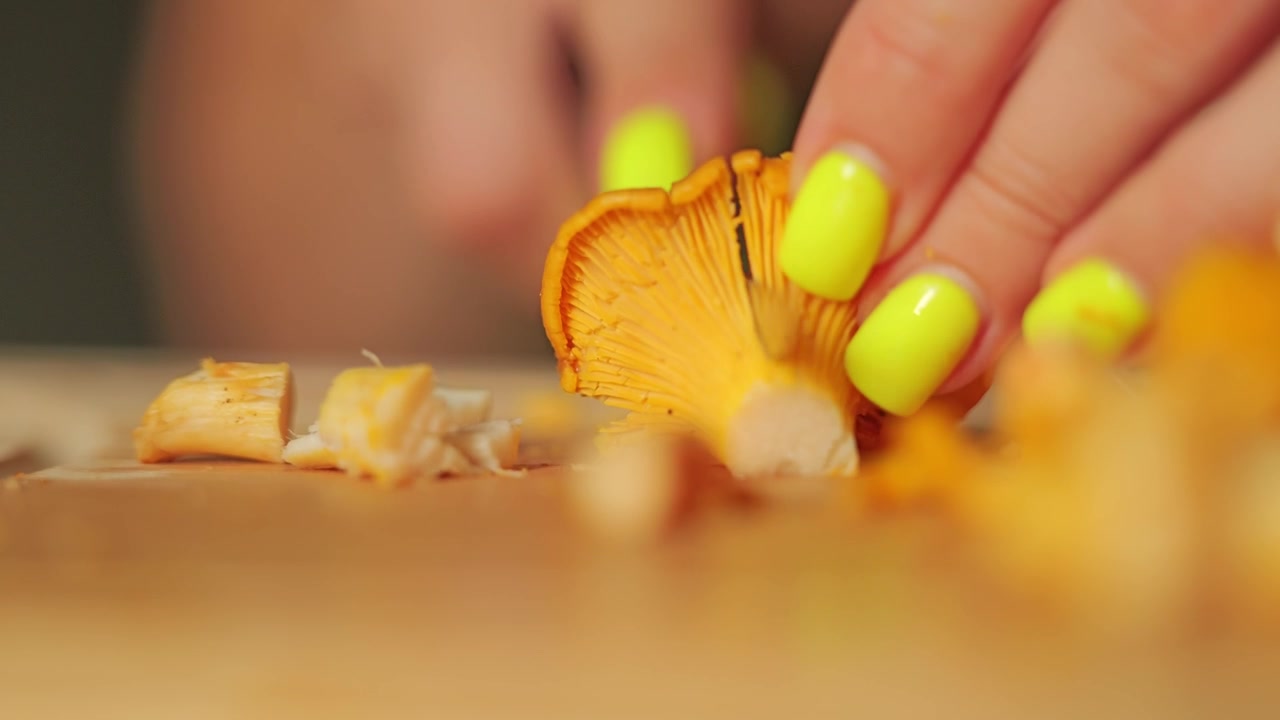 Bright yellow green manicure preparing fresh forest mushrooms indoors